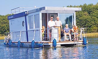 unser Hausboot Febomobil 990 auf einem kleine See mit einer Familie auf der Terrasse